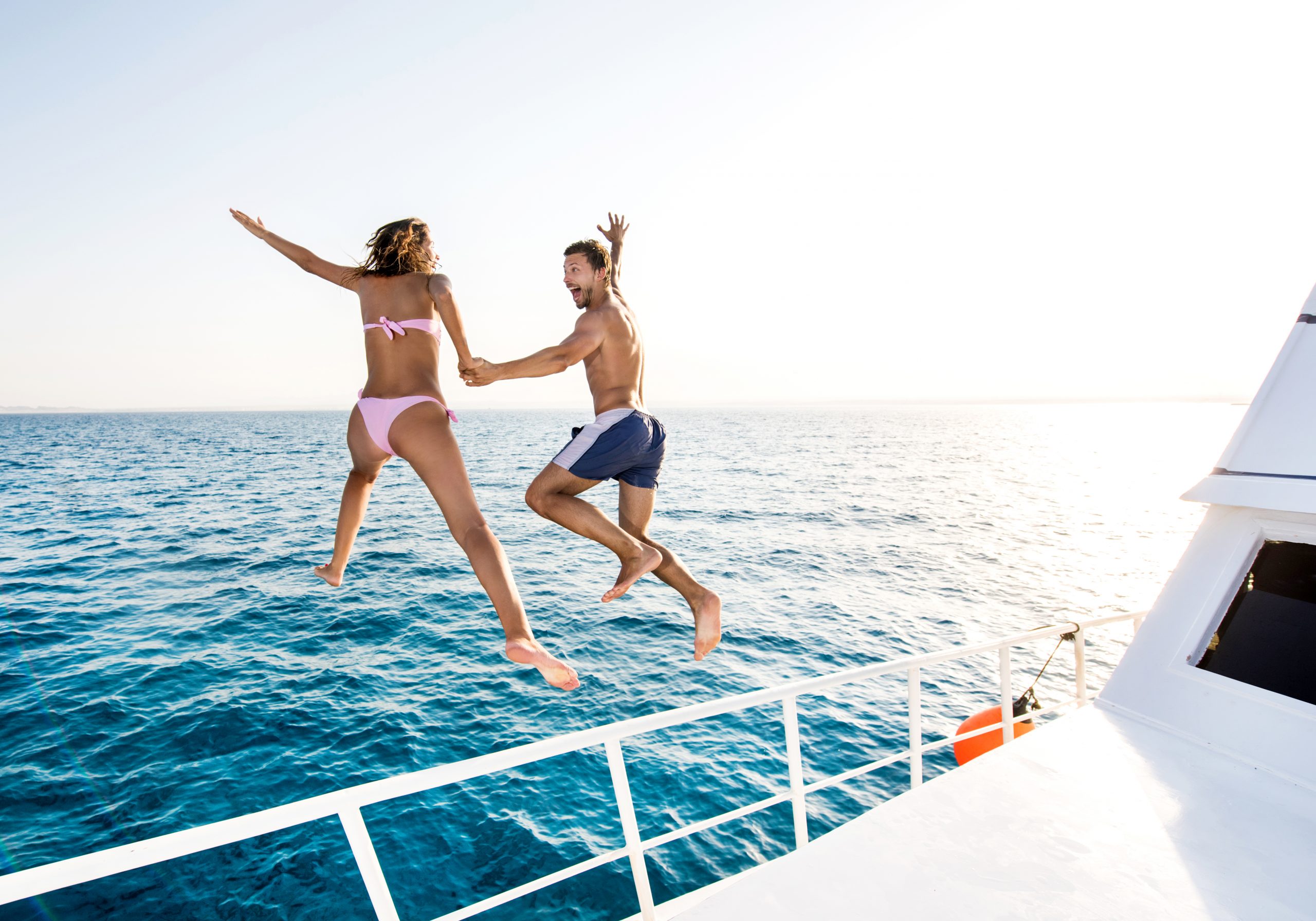 Cheerful couple jumping from boat.